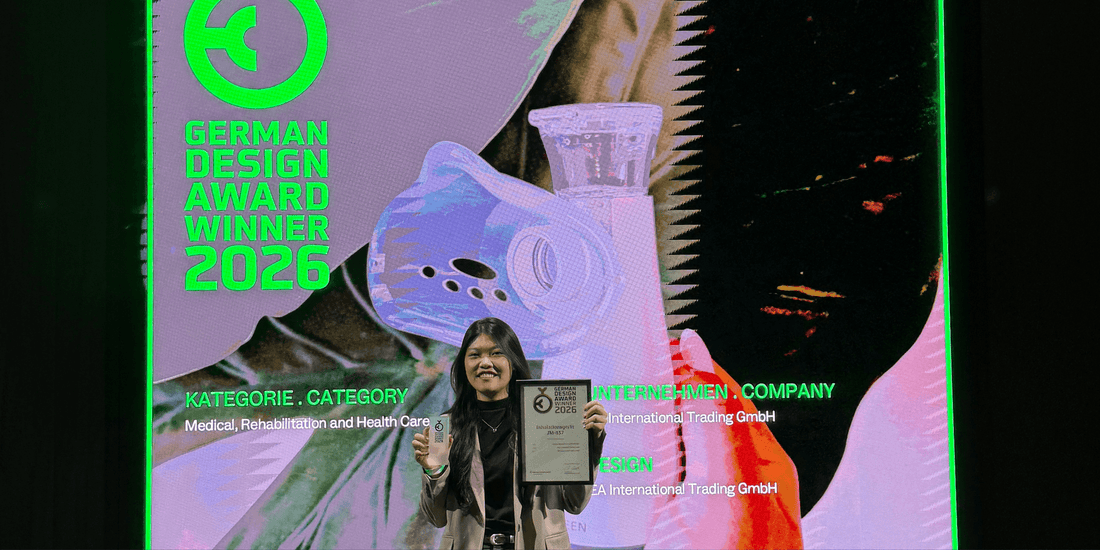 Frau hält eine Urkunde vor einer German-Design-Award-Winner-2026-Leinwand mit abgebildetem Inhalator.