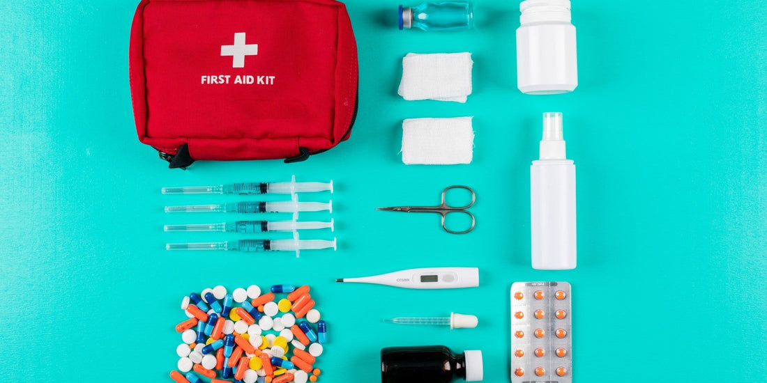 Erste Hilfe Set für unterwegs: rote Tasche mit Pflastern, Binden, Schere und Verbandmaterial auf türkisem Hintergrund