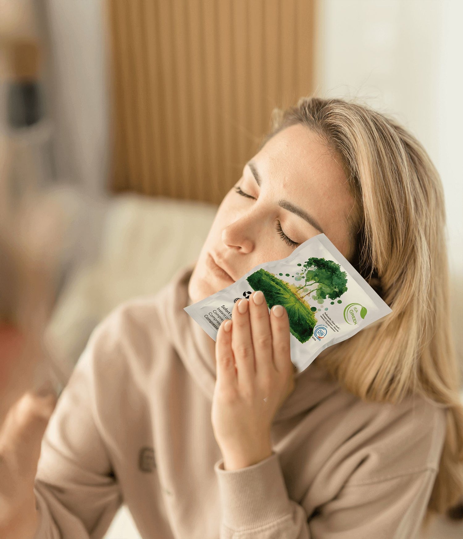 Frau hat Schmerzen im Gesicht und benutzt eine Sofortkaltkompresse der Marke IEA Green 