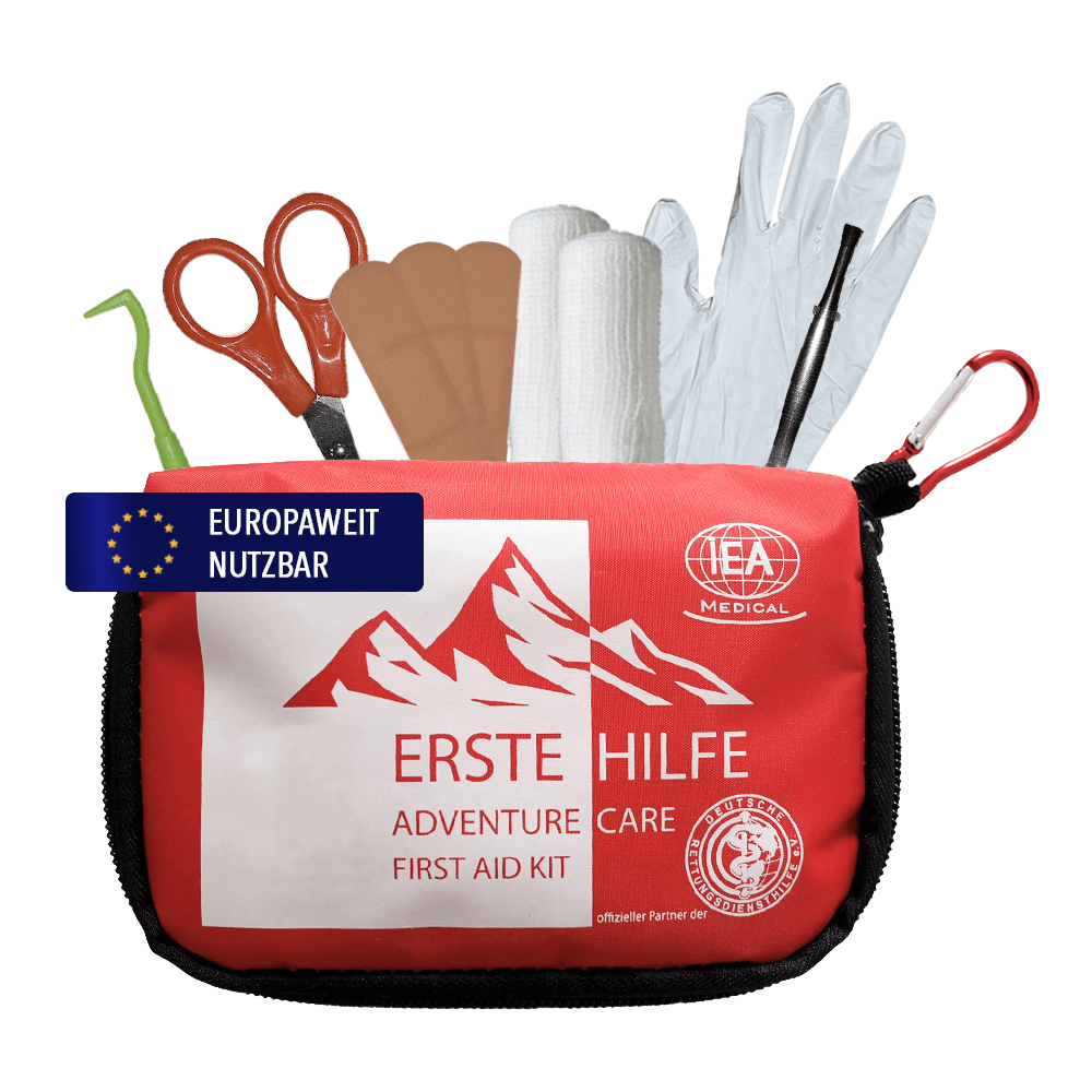 Geöffnete rote Erste-Hilfe-Tasche mit Schere, Zeckenkarte, Pflastern, Verband, Handschuhen und Karabiner.
