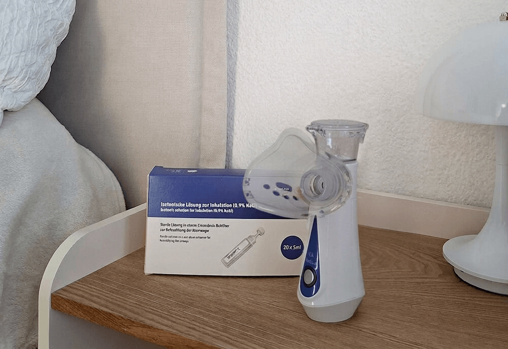 Auf einem Nachttisch stehen die IEA Medical Kochsalzlösung und das IEA Medical Inhalationsgerät