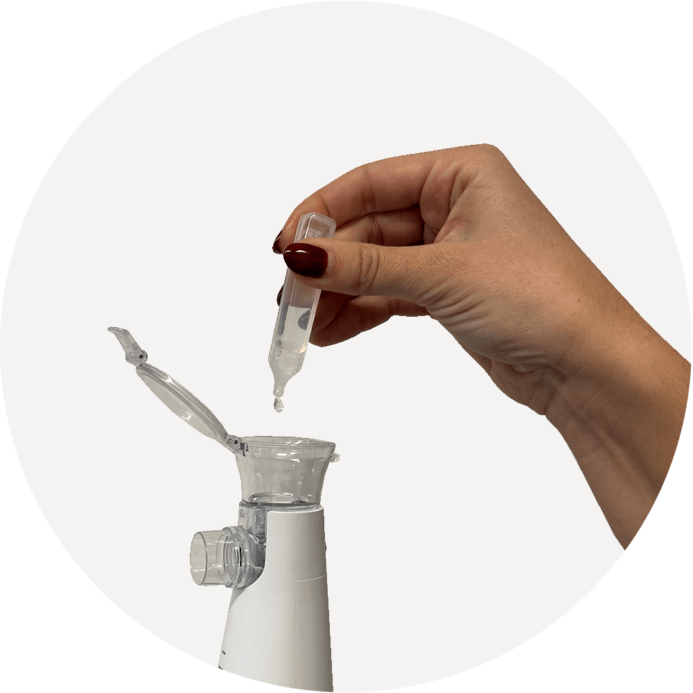 Hand befüllt den geöffneten Wassertank eines Inhaliergeräts mit einer Kochsalzlösung; Demonstration des Einfüllens.