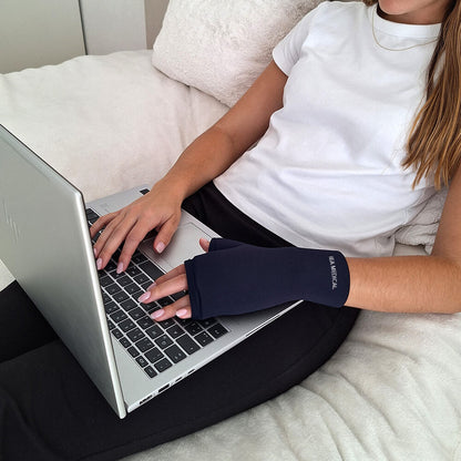 Frau tippt am Laptop und trägt dabei dunkelblauen Kühlhandschuh mit IEA-Medical-Schriftzug.