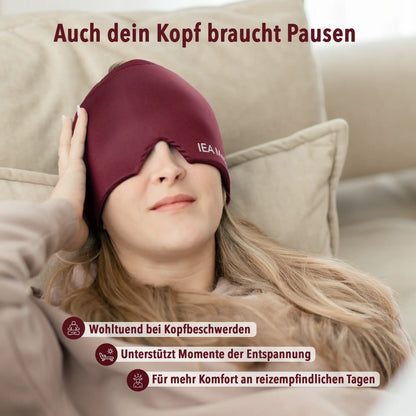 Frau liegt entspannt auf dem Sofa und trägt eine bordeauxrote Kopfmaske von IEA Medical über Stirn und Augen.