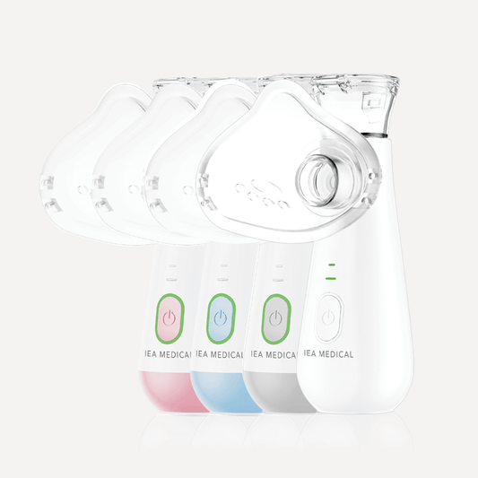 Vier Ultraschall-Inhalatoren in Reihe in den Farben Rosa, Blau, Grau und Weiß mit transparenten Masken.