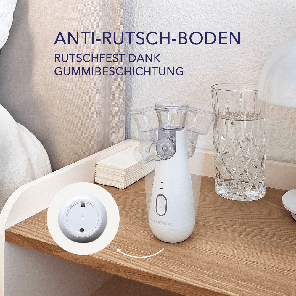 Inhalator auf Holznachttisch neben Wasserglas; Detailkreis zeigt rutschfeste Gummibeschichtung am Boden.