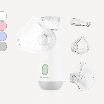 Weißer Inhalator mit grünem Einschaltknopf und Maske, dazu Mundstück, zwei Masken und Farbmuster links.