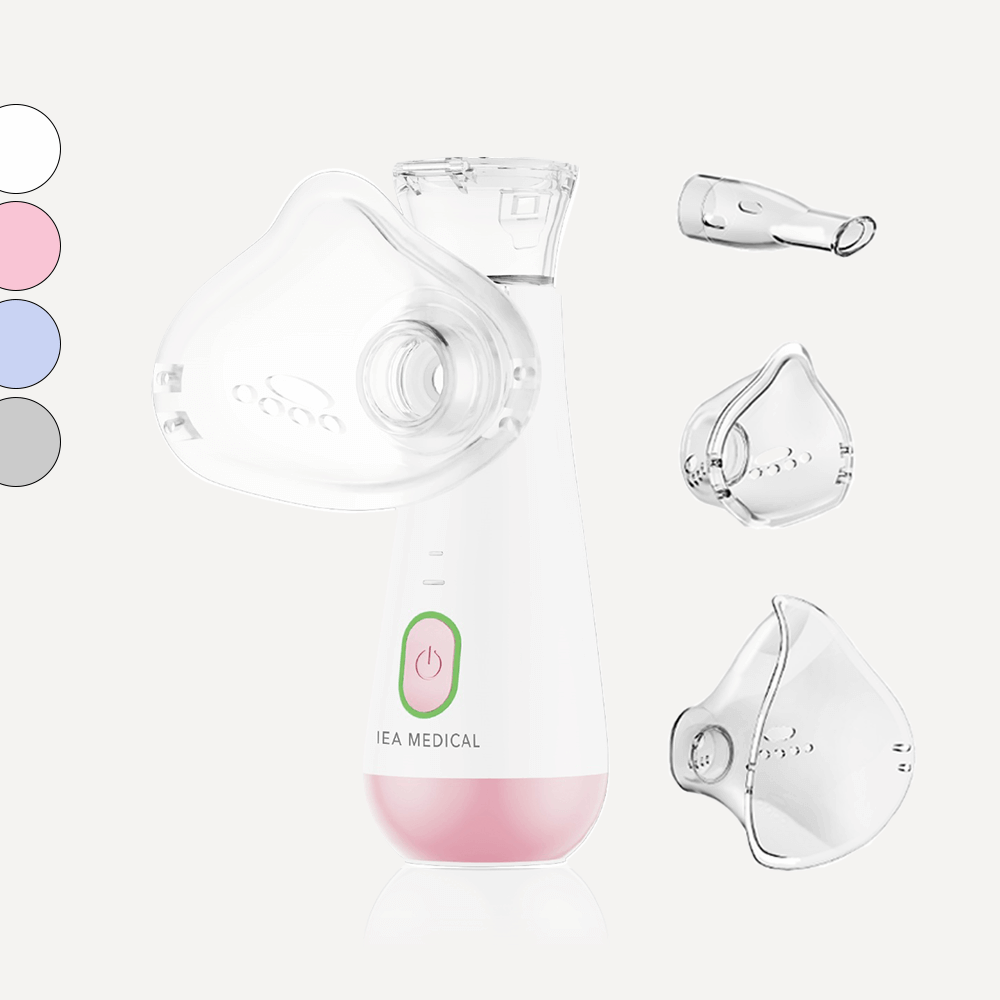 Inhalator mit rosa Unterteil und grünem Einschaltknopf samt Maske, Mundstück, zwei Masken und Farbmuster.