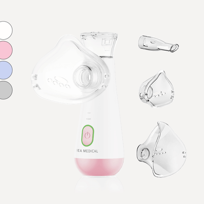 Inhalator mit rosa Unterteil und grünem Einschaltknopf samt Maske, Mundstück, zwei Masken und Farbmuster.