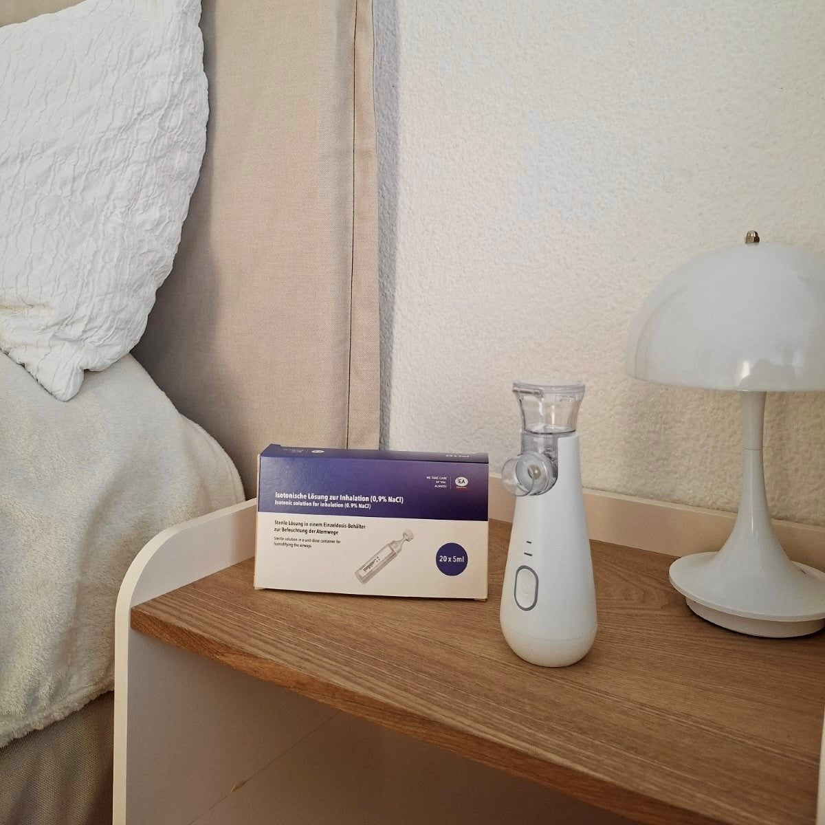 Inhalator und Kochsalzlösung von IEA Medical stehen auf dem Nachttisch