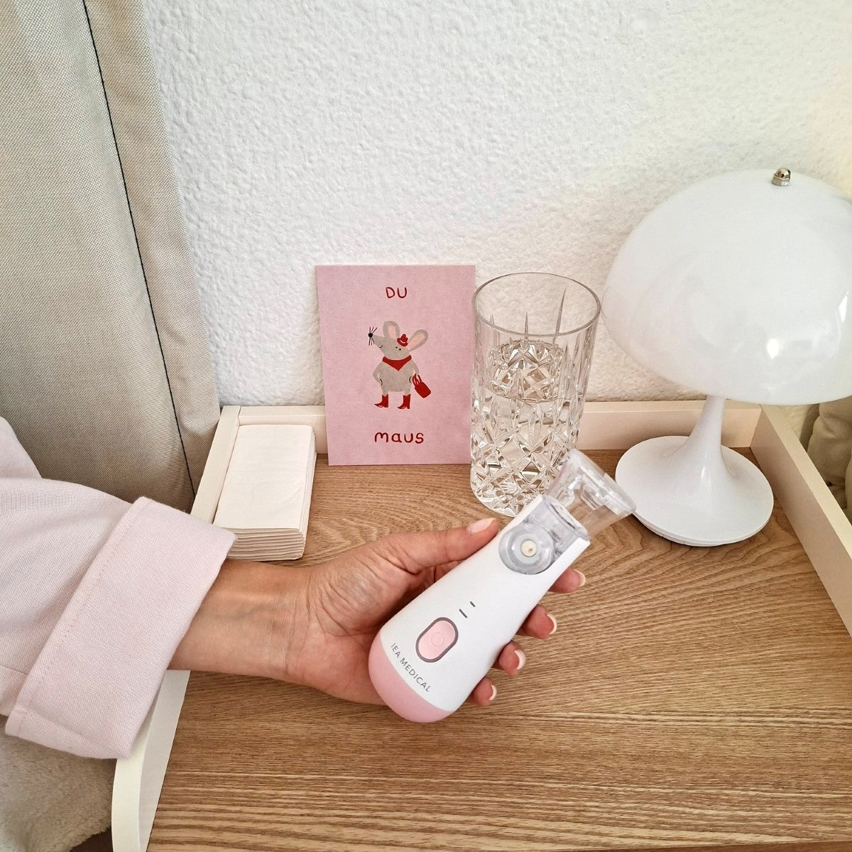 Rosa Inhalator von IEA Medical auf dem Nachttisch mit Grußkarte im Hintergrund